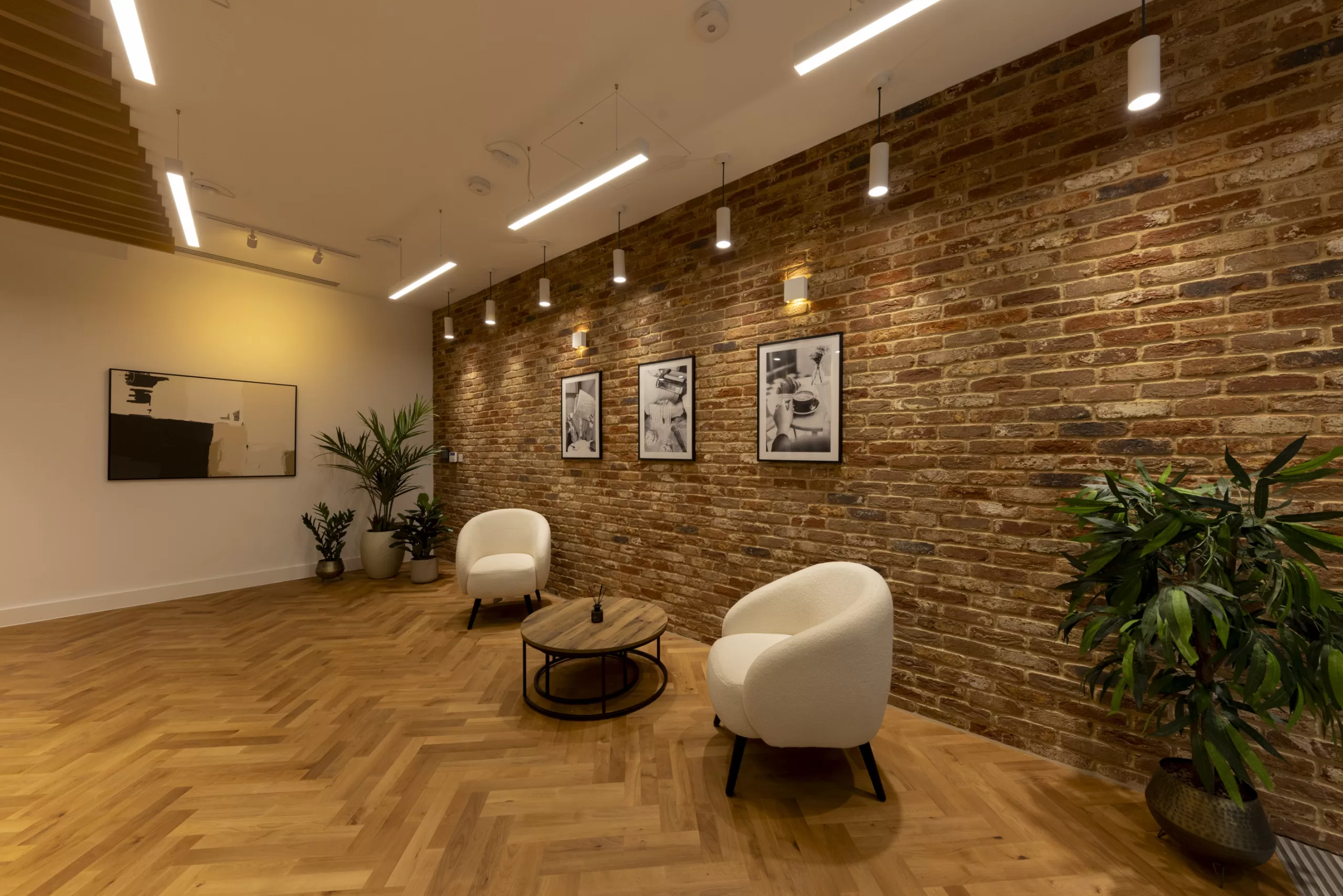 LED suspended downlights and battens against a brick wall with chairs and table